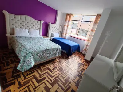 a bedroom with a bed and a purple wall at SUMAQ PUNUY HOSTEL - Lima Airport in Lima