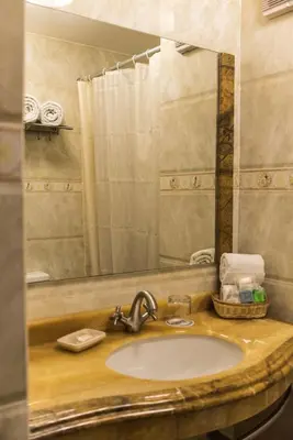 a bathroom sink with a mirror and a shower at Apart Hotel El Doral in Lima