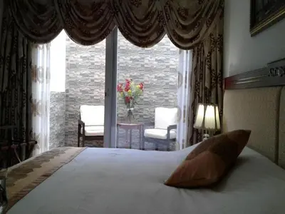 a bedroom with a bed and a window with chairs at Apart Hotel El Doral in Lima