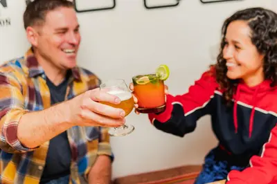 a man and woman holding glasses of beer at Dragonfly Hostels Cusco in Cusco