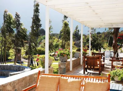 a white pergola with chairs and tables on a patio at Hotel Los Palomos in Lunahuaná