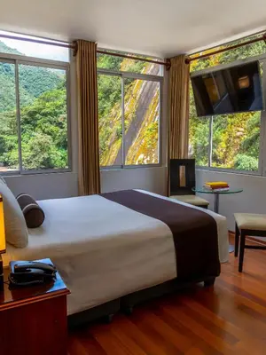 a bedroom with a large bed and large windows at Hotel Ferré Machu Picchu in Machu Picchu
