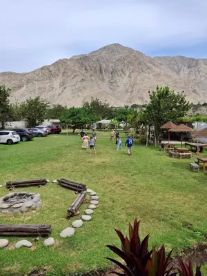a group of children playing in a field with mountains in the background at La Fortaleza del Inca in Lunahuaná