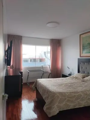 a bedroom with a bed and a desk and a window at Céntrico, acogedor y amplio apartamento en Magdalena in Lima