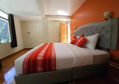 a bedroom with a large bed with an orange wall at Hotel Horizonte in Machu Picchu