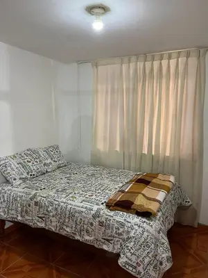 a bedroom with a bed and a window with a blanket at Palmeras house in Ica