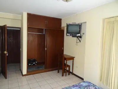 a room with a tv and a table and a desk at Hotel Nova in Lima