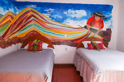 a room with two beds with a painting on the wall at Millas House Cusco in Cusco
