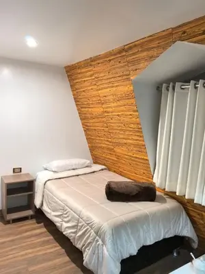 a bedroom with a bed with a wooden headboard at Vallecito Lodge in Muyurina