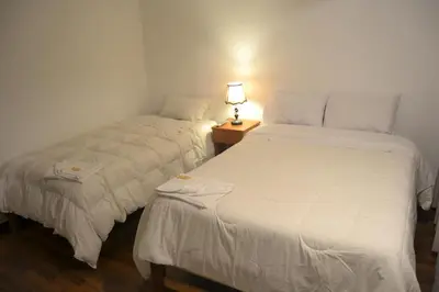 two beds in a room with a lamp on a table at Apu Wasi in Cusco