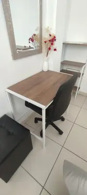 a wooden table with a chair and a vase on it at Sumaq AirPort in Lima