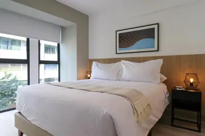 a bedroom with a large white bed and two windows at One By Wynwood House in Lima