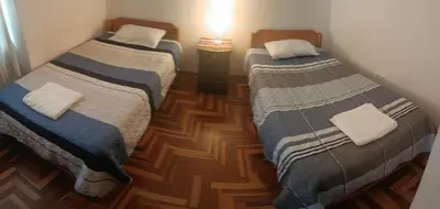 two beds in a small room with wooden floors at WaskarWasi in Cusco