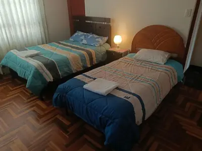 a bedroom with two beds and a lamp in it at WaskarWasi in Cusco