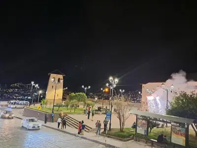 a group of people walking around a square at night at HOSTAL La RASA in Cusco