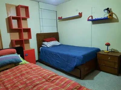 a bedroom with a bed and a dresser with a blue blanket at Amplio, y confortable departamento en San Miguel in Lima