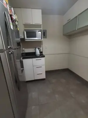 a kitchen with a stainless steel refrigerator and white cabinets at Amplio, y confortable departamento en San Miguel in Lima
