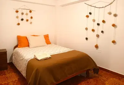 a bedroom with a bed with orange pillows and decorations at Cuesta del Inka in Cusco