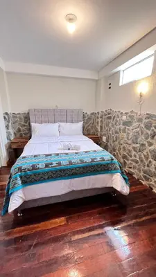 a bedroom with a large bed with a stone wall at intikilla hostal in Ollantaytambo