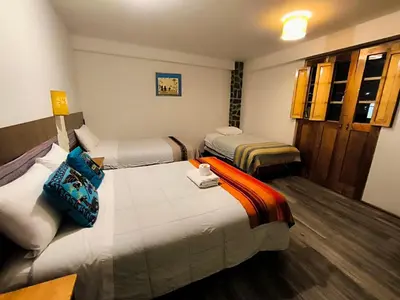 a hotel room with three beds in a room at hostal Balcon de Piedra in Urubamba