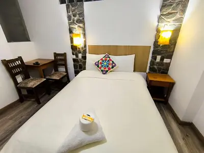 a bedroom with a large white bed and two chairs at hostal Balcon de Piedra in Urubamba