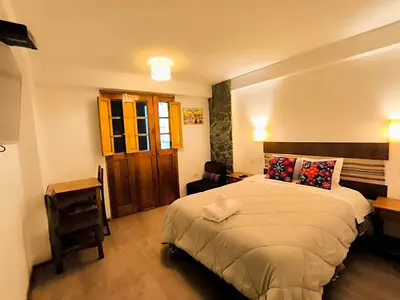 a bedroom with a bed and a desk and a chair at hostal Balcon de Piedra in Urubamba