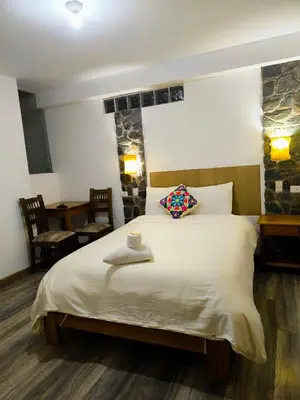 a bedroom with a large white bed with a pillow at hostal Balcon de Piedra in Urubamba