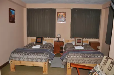 a hotel room with two beds and two chairs at Hostal Goya Andina in Cusco