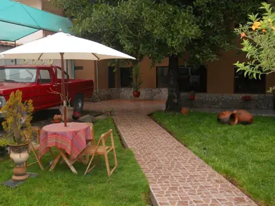 a table and chairs and an umbrella in a yard at Hostal Goya Andina in Cusco