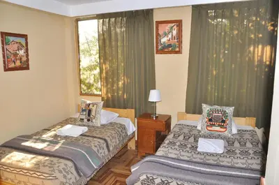 two beds in a room with a window at Hostal Goya Andina in Cusco