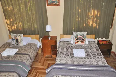two beds in a room with green curtains at Hostal Goya Andina in Cusco