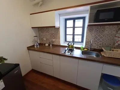 a kitchen with white cabinets and a sink and a window at Mini Apart II - Sumaq Wasi ALBA in Cusco