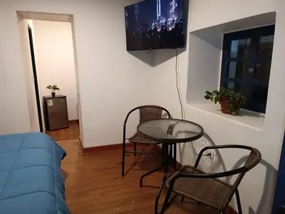 a living room with a table and chairs and a tv at Mini Apart II - Sumaq Wasi ALBA in Cusco