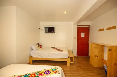 a room with two beds and a red door at Hotel Ruta Amazónica Machupicchu in Machu Picchu