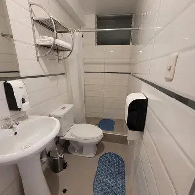 a white bathroom with a toilet and a sink at Hotel Ruta Amazónica Machupicchu in Machu Picchu