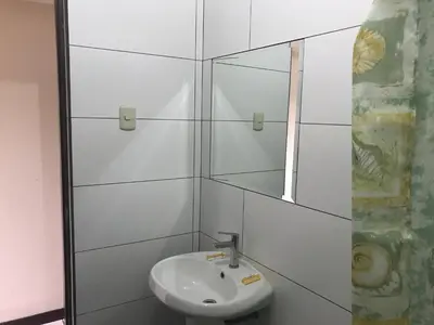 a white bathroom with a sink and a mirror at Hostal La Cascada in Lima