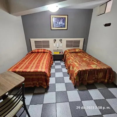 a room with two beds and a checkered floor at Hostal La Cascada in Lima