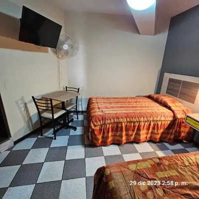 a room with two beds and a table and a television at Hostal La Cascada in Lima