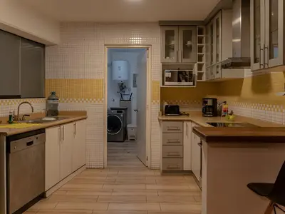 a kitchen with white cabinets and yellow tile walls at Acogedor 2BR Miraflores - Tovar in Lima