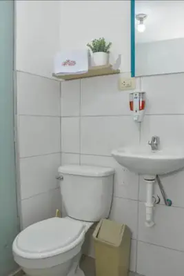 a white bathroom with a toilet and a sink at Apu House Monoambiente in Cusco