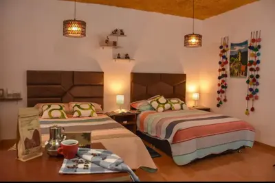 a bedroom with two beds and a table and lamps at Apu House Monoambiente in Cusco