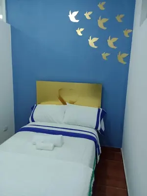 a bed with a blue wall with birds on it at Puerta Azul Hospedaje in Lima