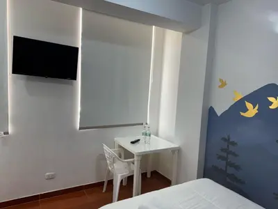 a bedroom with a bed and a table and a tv at Puerta Azul Hospedaje in Lima