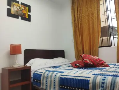 a bedroom with a bed with a blue blanket and a window at Sumaq Wasi Caminos Del Inca in Lima