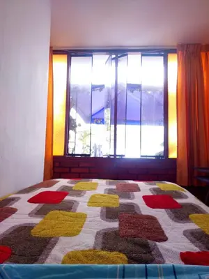 a bedroom with a quilt on a bed with a window at Sumaq Wasi Caminos Del Inca in Lima