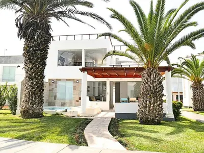 a house with two palm trees in front of it at Casa entera con piscina y salida a la playa in Salinas