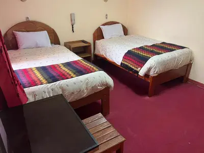 a room with two beds and a laptop on a table at HOSTAL HUAYNA HOUSE GO in Cusco