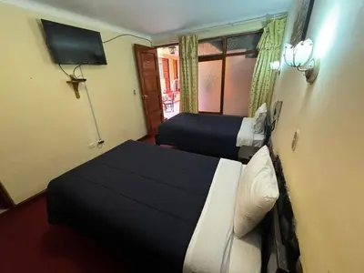 a hotel room with two beds and a television at HOSTAL HUAYNA HOUSE GO in Cusco