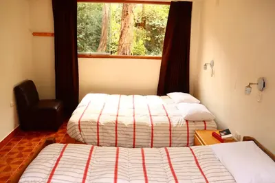 two beds in a hotel room with a window at Full Moon Eco Lodge in Ollantaytambo