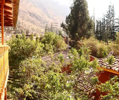 a garden with bushes and trees and a mountain at Full Moon Eco Lodge in Ollantaytambo